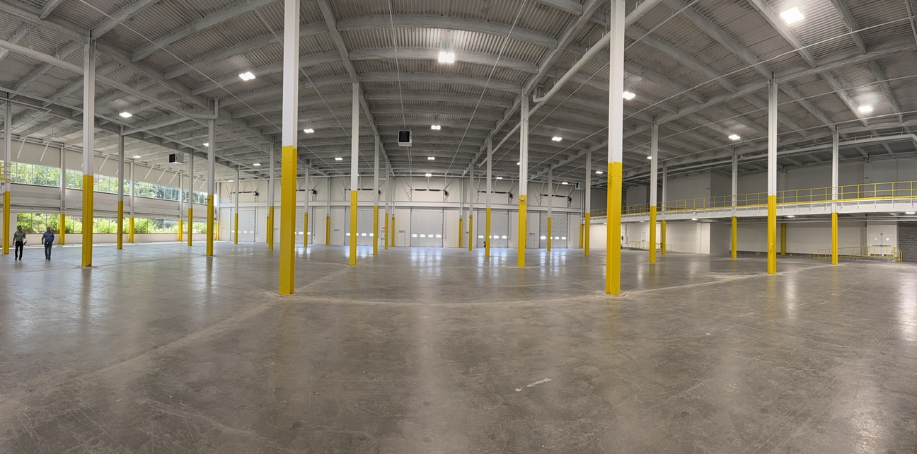 Panorama of the open industrial floor of CitiCorp Building 3, yellow painted steel columns running down the bays to new loading doors