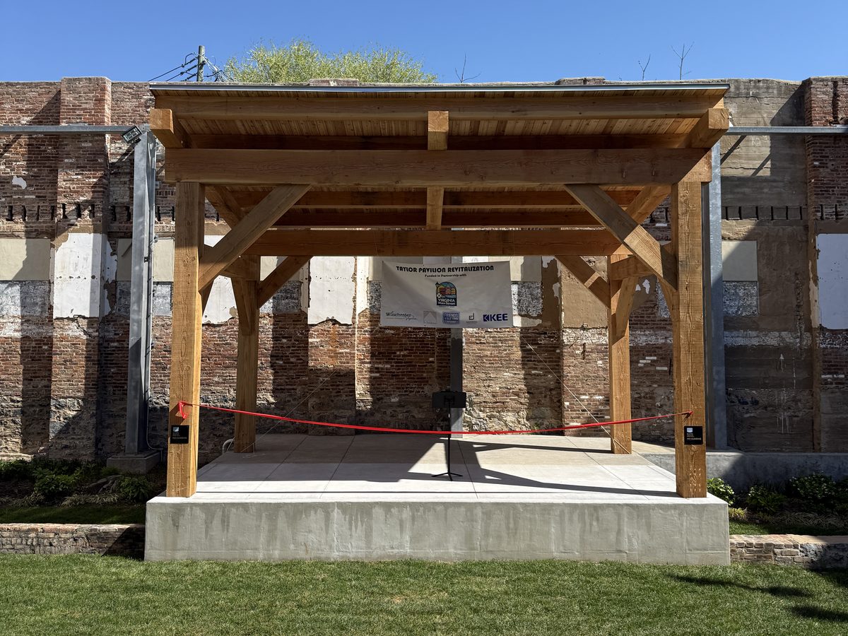 Timber frame open air stage of the Taylor Pavilion set against a historic brick wall
